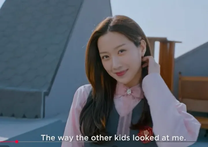 Младо момиче, което гледа към камерата, прибира кичур коса зад ухото си.