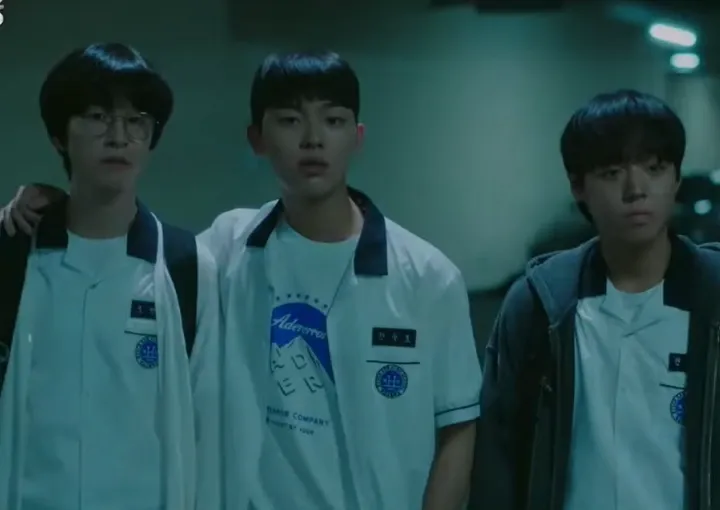 3 момчета в училищни униформи гледат към камерата. 